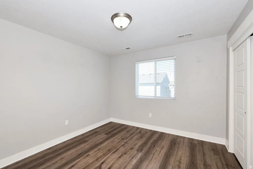 Interior room featuring wood-finish flooring, light-toned walls, and a window with horizontal blinds