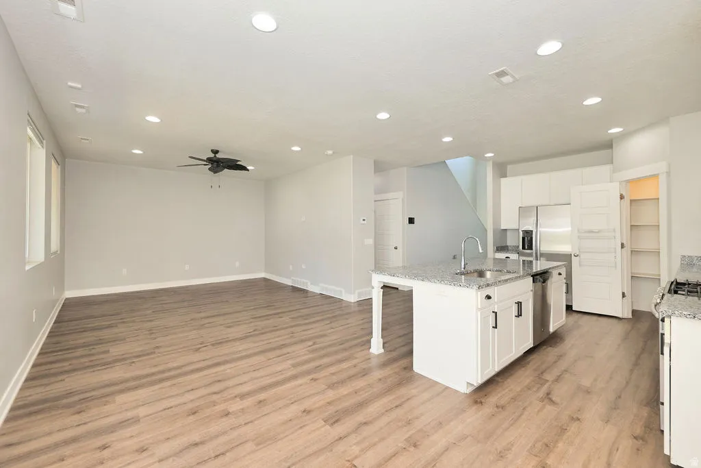Spacious open-concept living area featuring wood-finish flooring, recessed lighting, and a ceiling fan