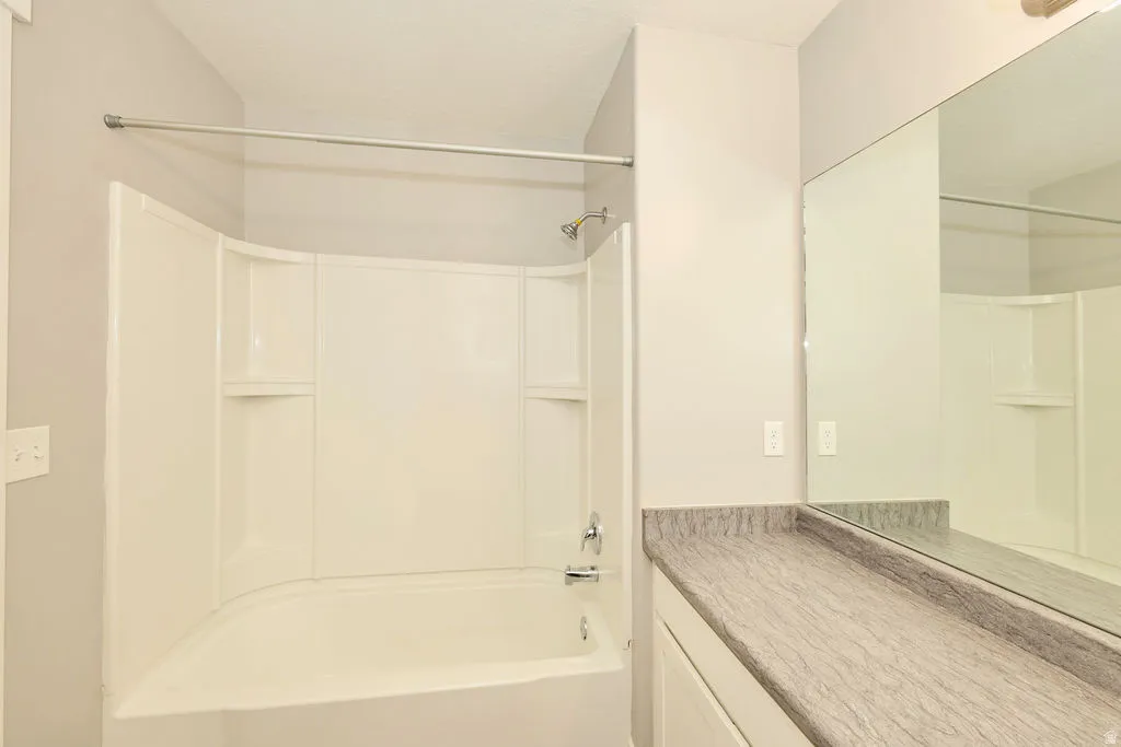 Bathtub and shower combination with integrated shelving, chrome fixtures, and a curved shower rod