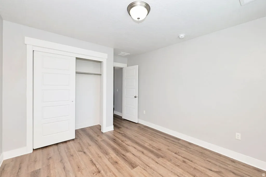 Room featuring wood-finish flooring, light gray wall paint, and white baseboards