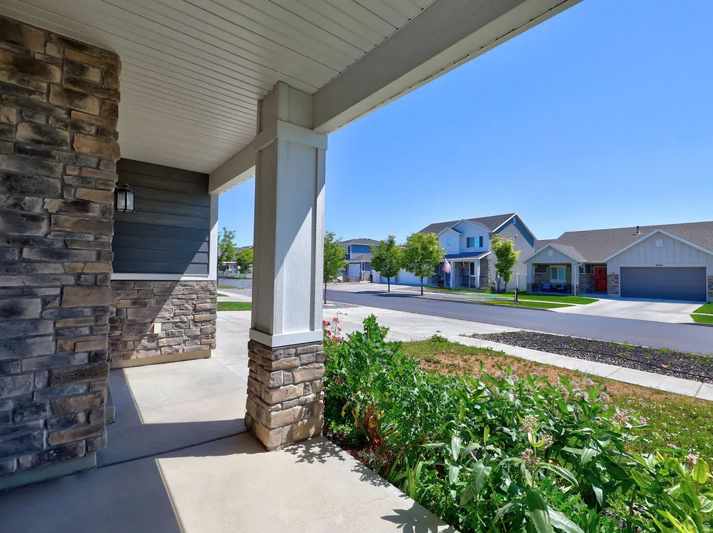 Covered front porch featuring stone veneer accents and a white column