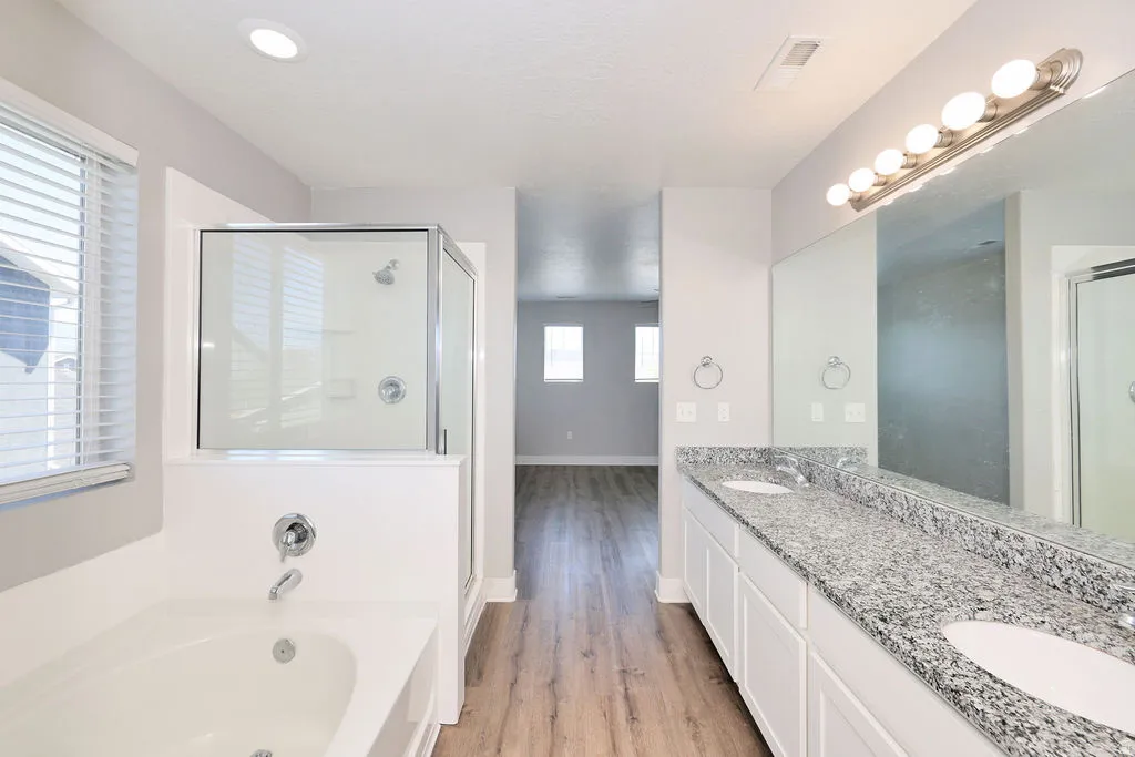 Bathroom featuring a dual vanity with a speckled countertop, integrated sinks, and a large wall mirror
