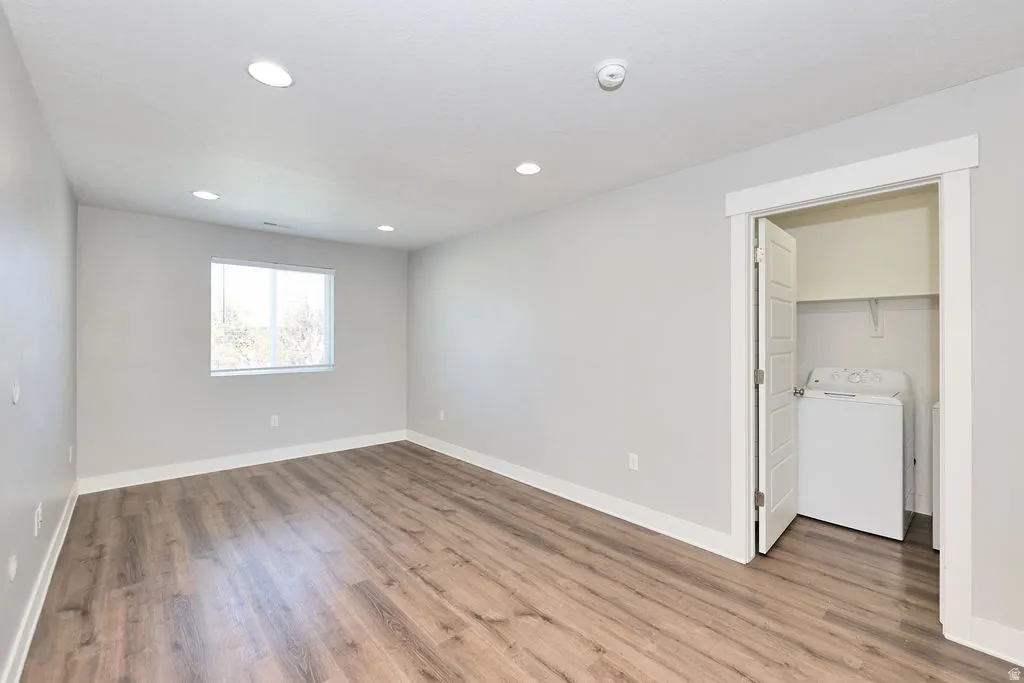 Spacious room featuring wood-finish flooring, recessed lighting, and a double-paned window
