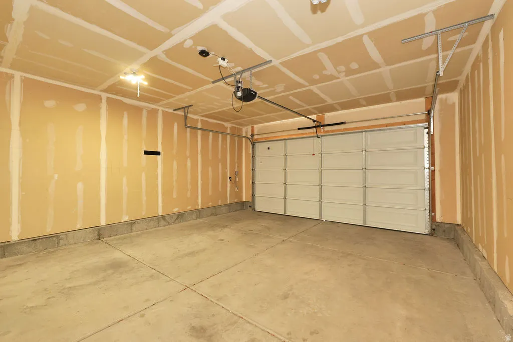 Spacious garage featuring a concrete floor, exposed drywall, and an overhead garage door with an automatic opener