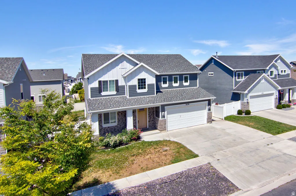 Two-story residence featuring a two-car garage, stone accents, and a covered porch entry