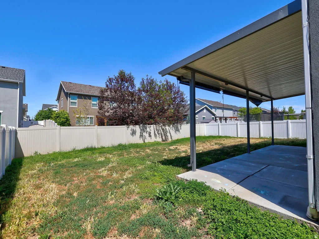 Expansive backyard featuring a covered patio, concrete slab, and perimeter fencing