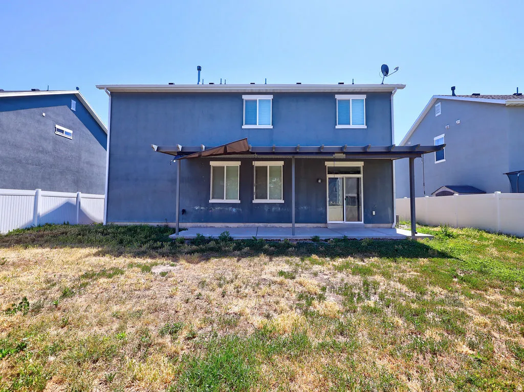 Rear exterior featuring a covered patio with metal framing, a sliding glass door, and multiple windows
