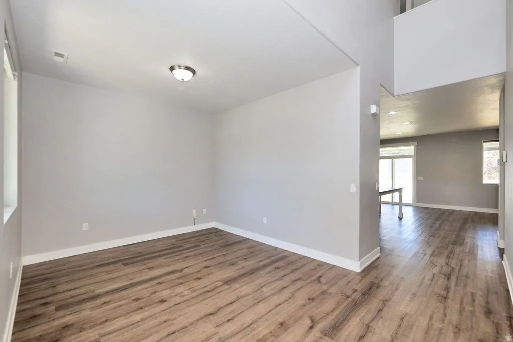 Spacious room featuring wood-finish flooring, light grey wall paint, and crisp white trim