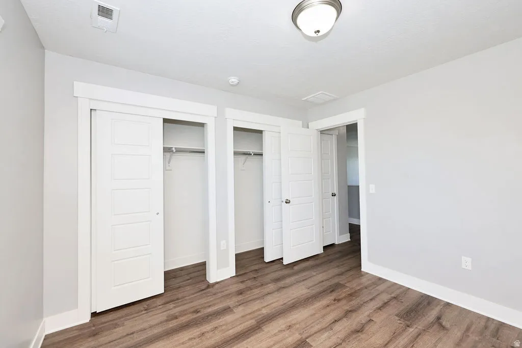 Room featuring wood-finish flooring, light grey walls, and white trim
