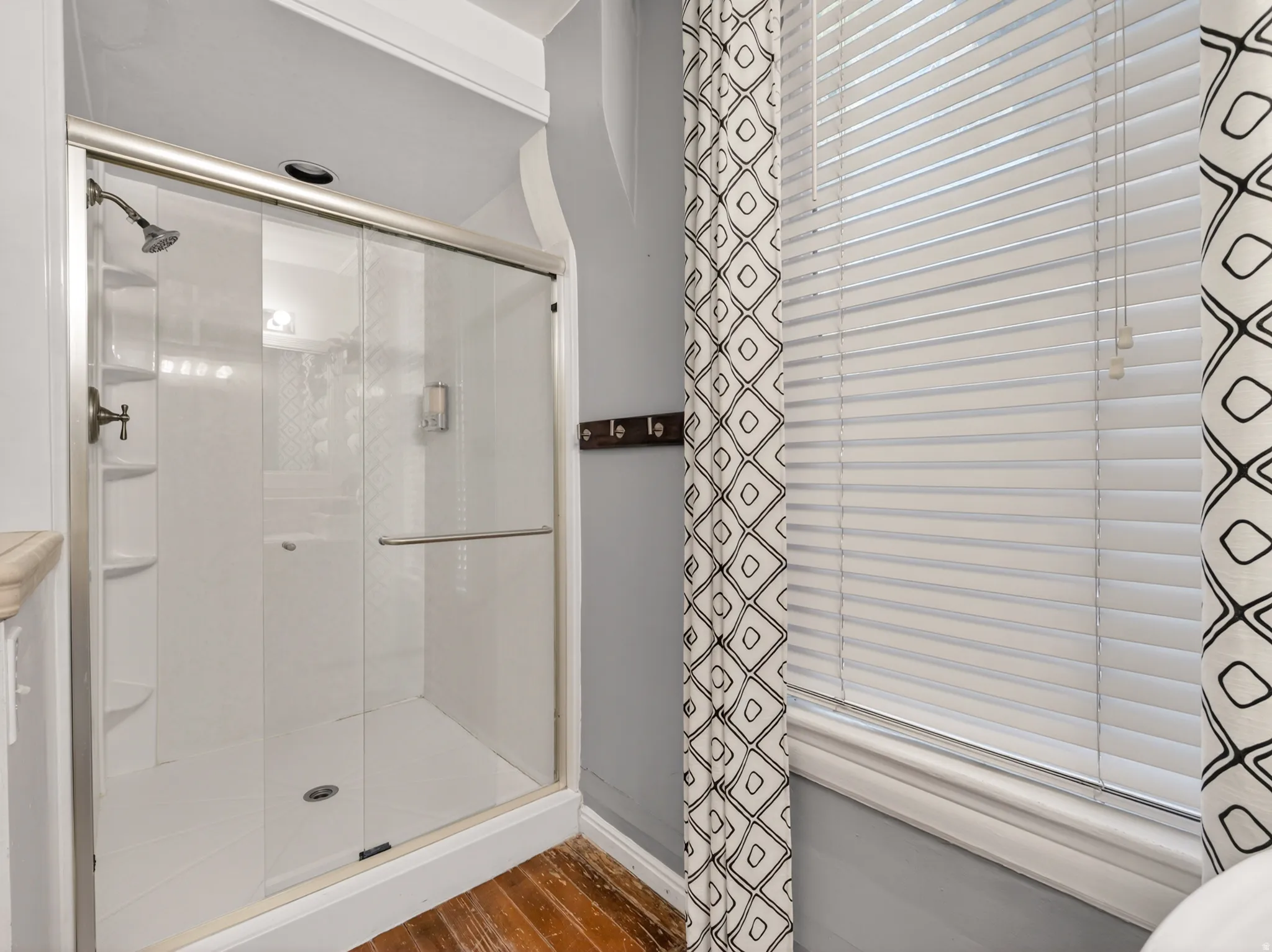 Glass-enclosed shower with a white tiled surround and integrated shelving