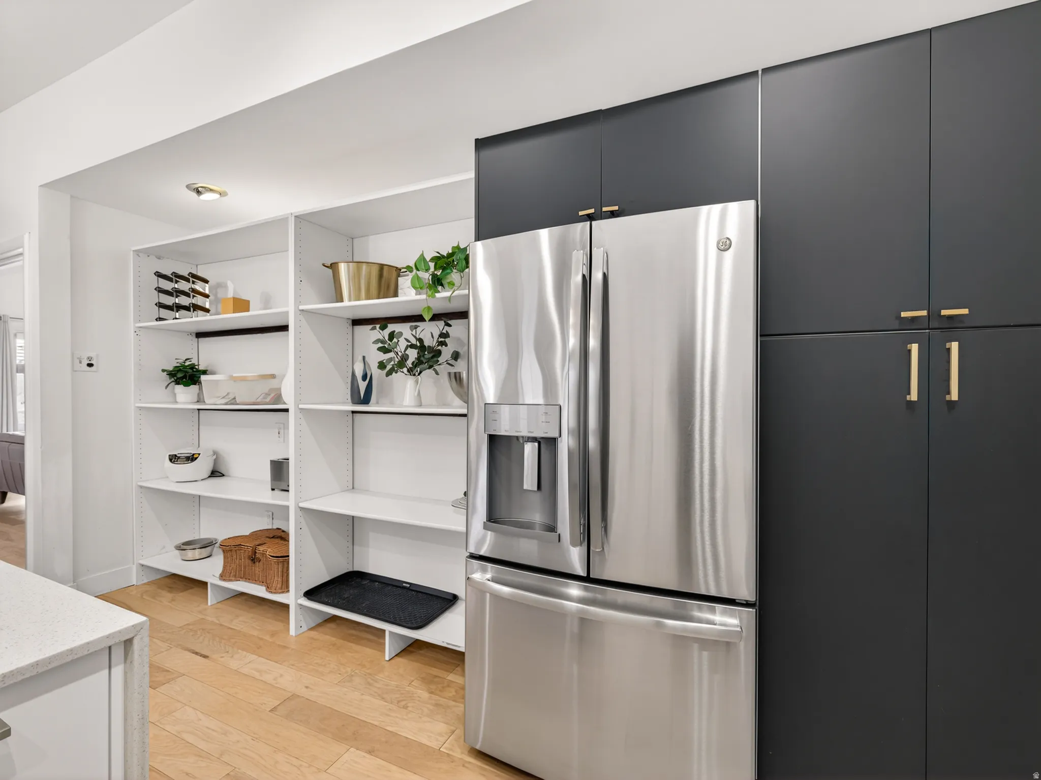 Stainless steel French door refrigerator alongside custom dark cabinetry with gold-tone hardware