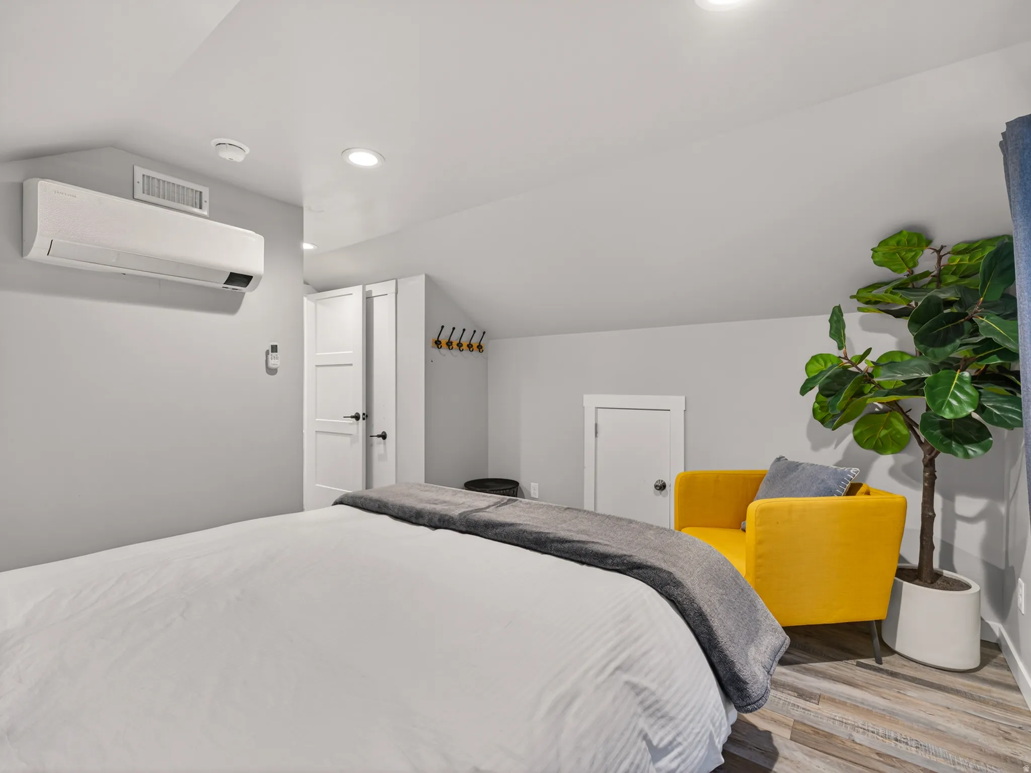 Recessed lighting illuminates the sloped ceiling and light gray walls