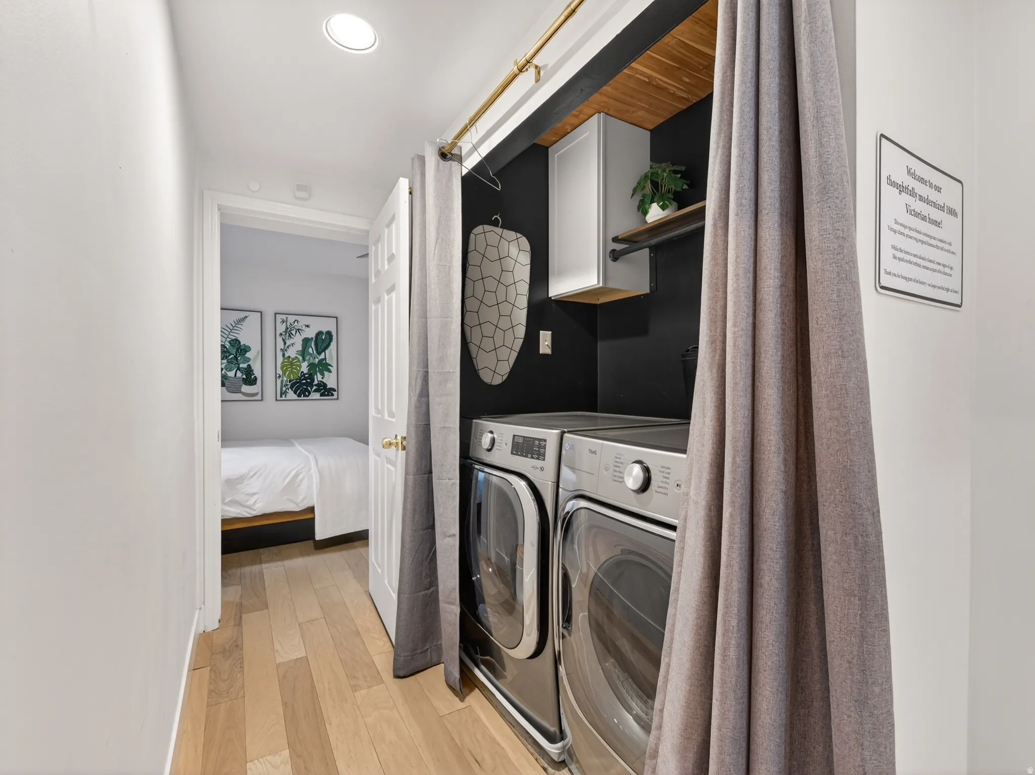 Dedicated laundry area featuring a stacked washer and dryer, wood-finish shelving, a recessed light fixture, and wood-finish flooring