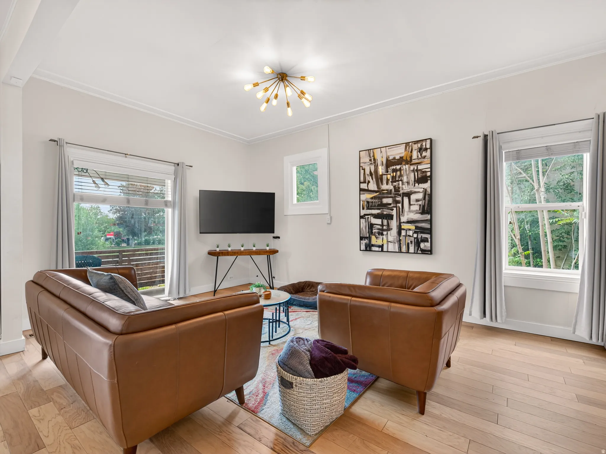 Living area with wood-finish flooring, white walls, and crown molding