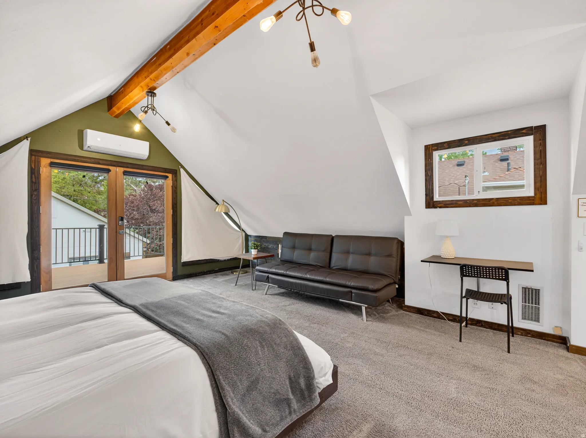 Attic space featuring vaulted ceilings with an exposed wood beam, wood-frame glass doors, a window with wood trim, wall-mounted climate control unit, and gray carpet flooring