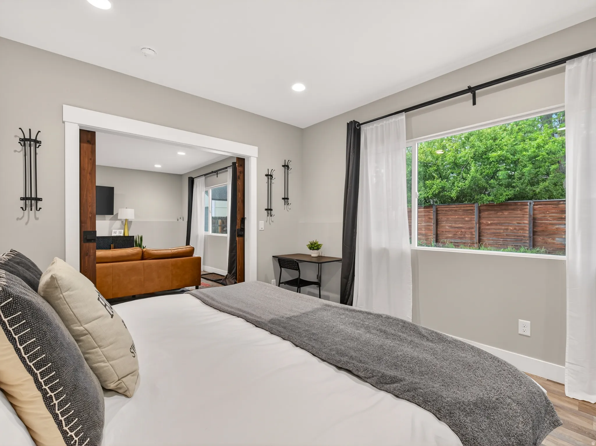 Bedroom featuring a wide window, wood-finish flooring, recessed lighting, and a barn door entry