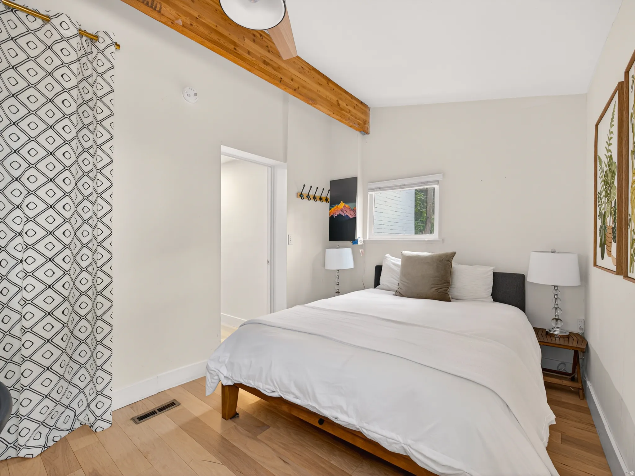 Bedroom featuring exposed wood ceiling beams, wood-finish flooring, a ceiling fan, and an integrated window