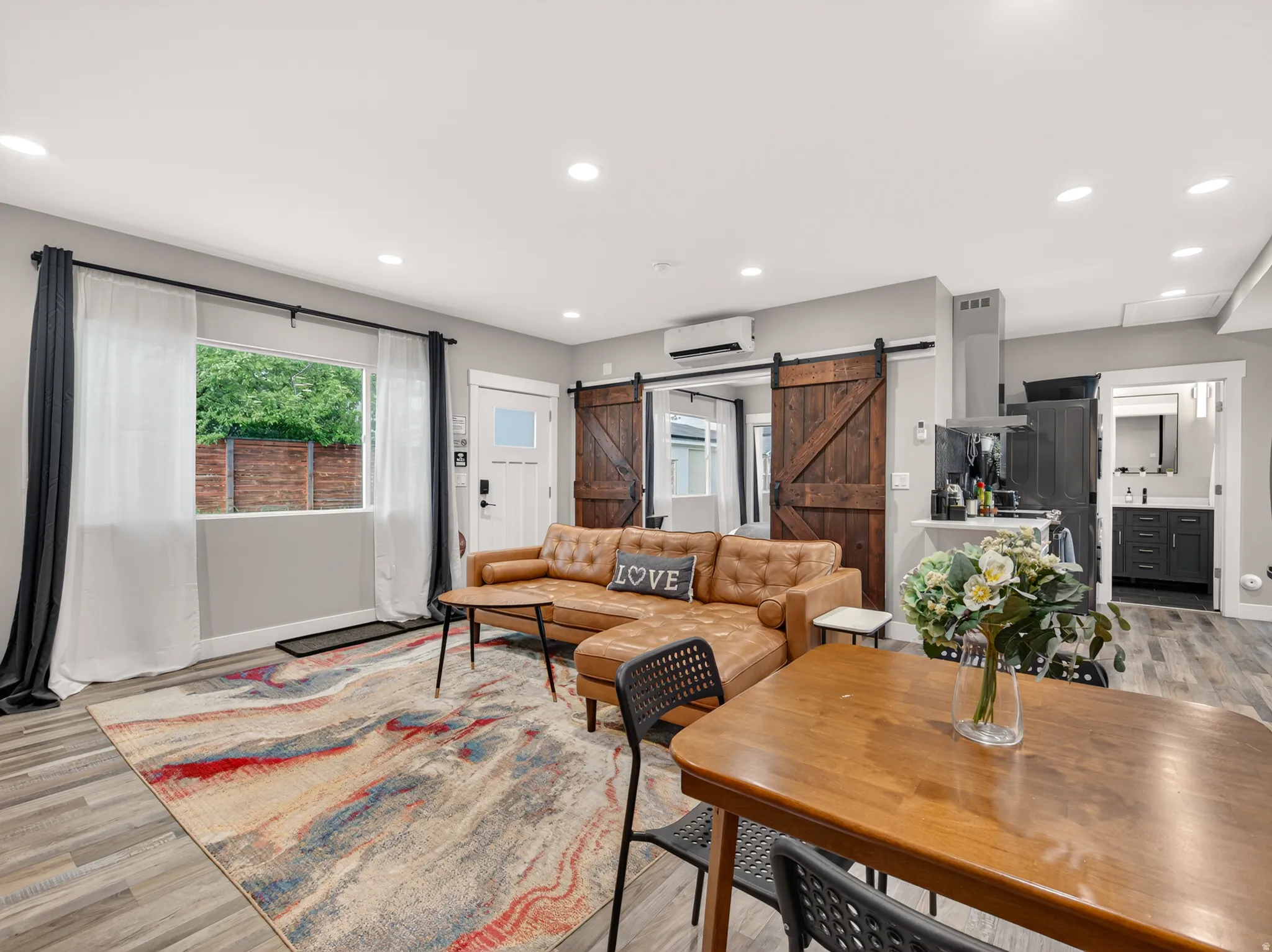 Open-concept living space featuring wood-finish flooring, recessed lighting, and a white front door