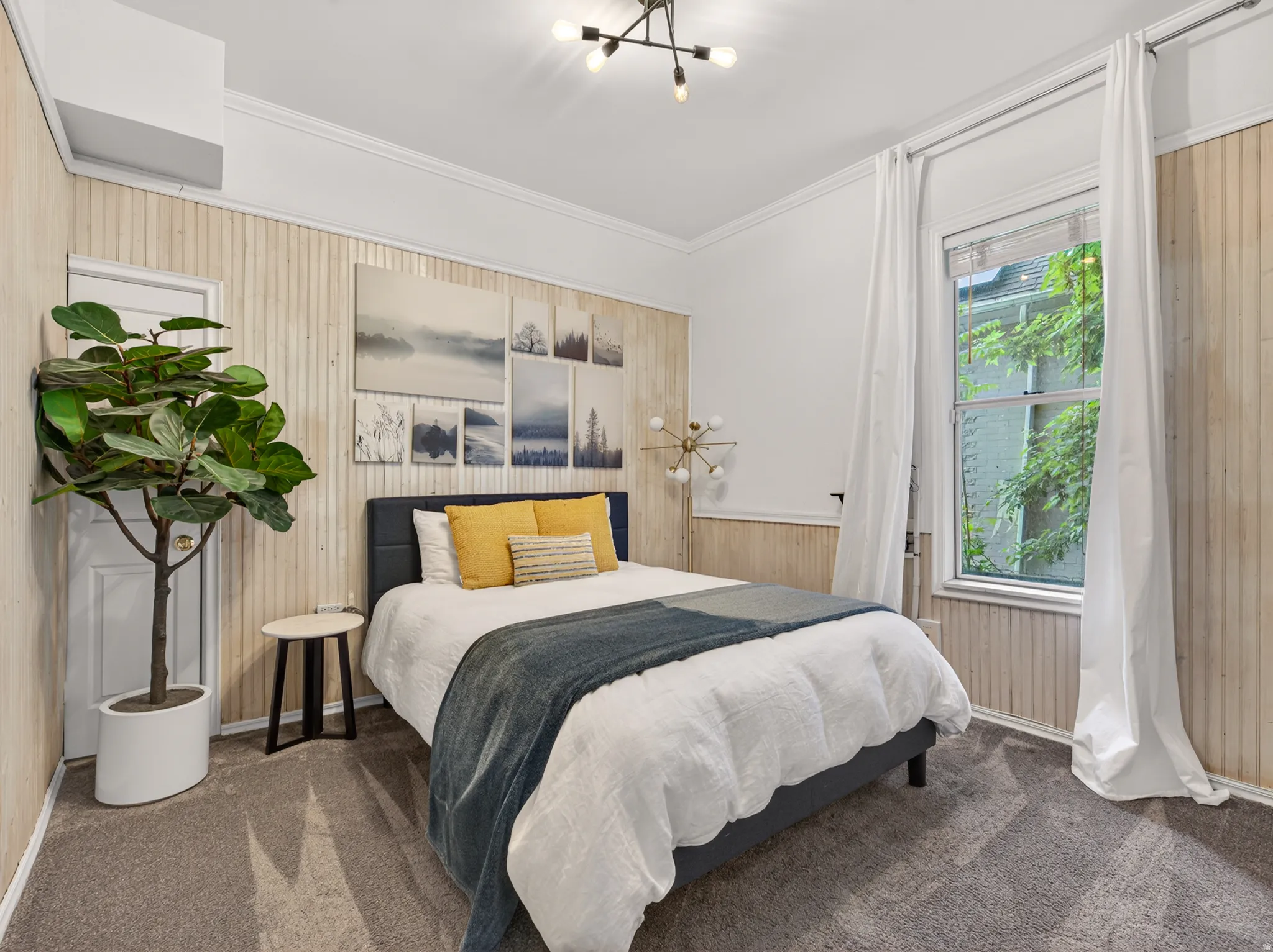 Hardwood paneling accents throughout, featuring crown molding, a high ceiling with a modern light fixture, and carpet flooring