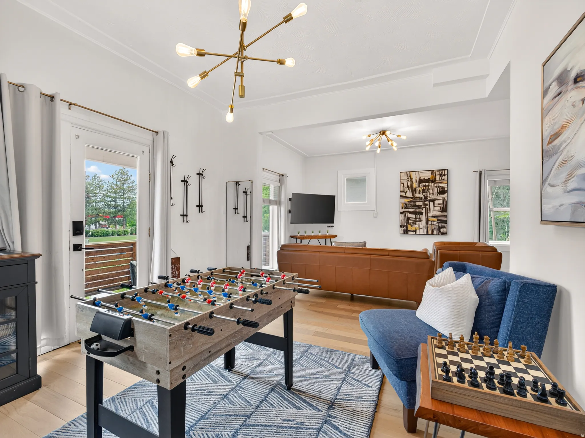 Bright interior space featuring light wood-finish flooring and a contemporary linear chandelier