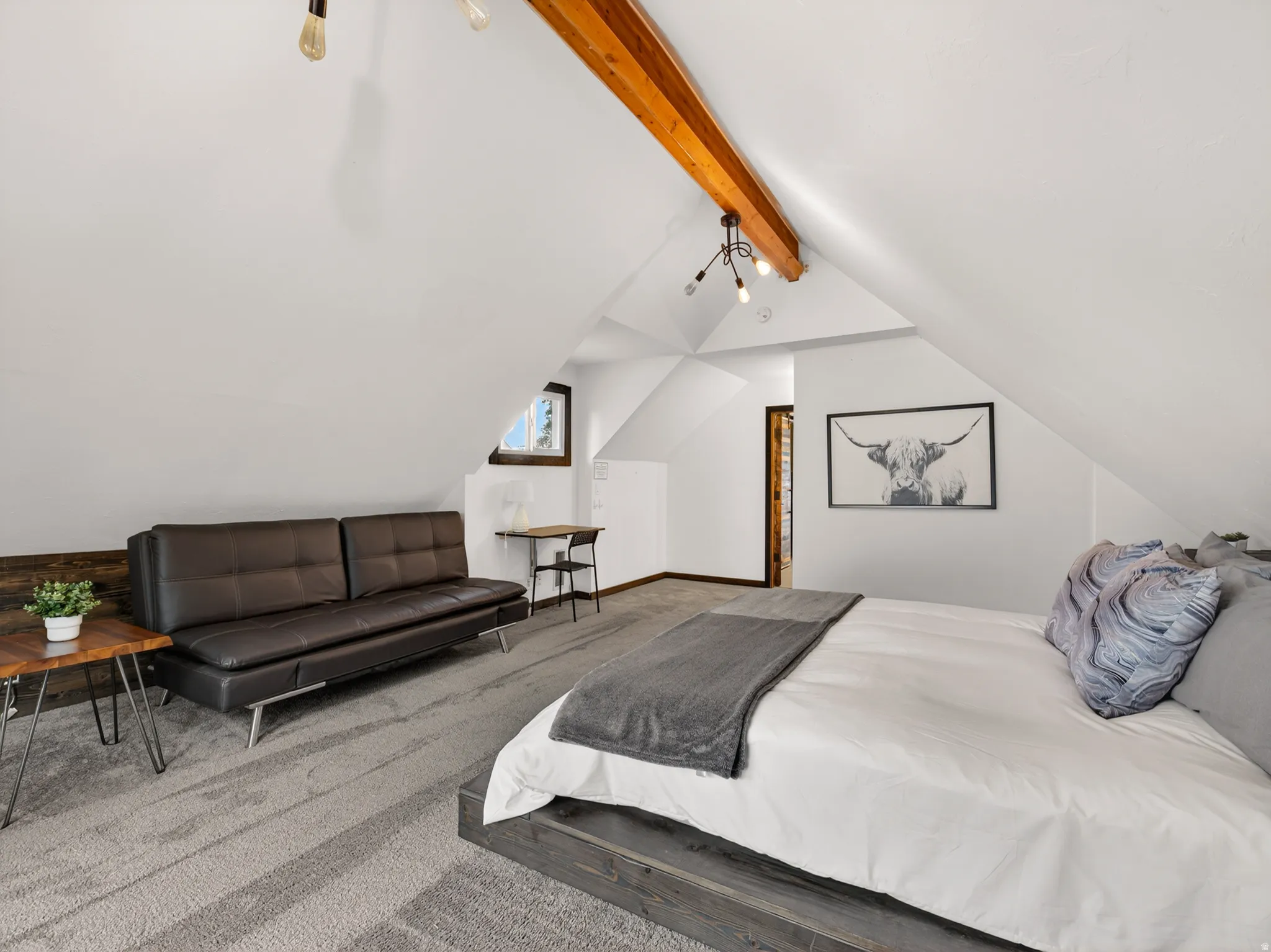 Attic space featuring sloped ceilings, exposed wood beams, and a window