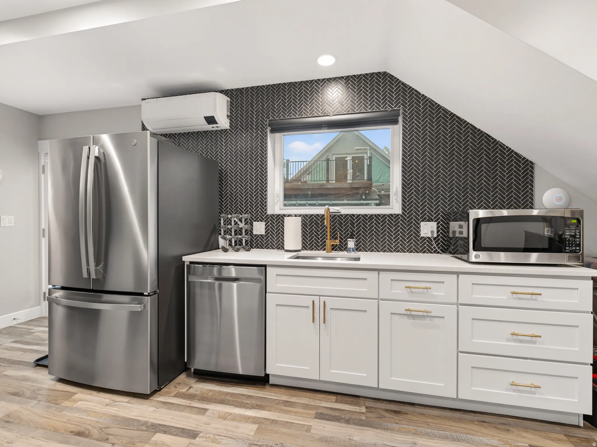 Kitchenette featuring white cabinetry with gold-tone hardware, a white countertop, and a black herringbone tile backsplash