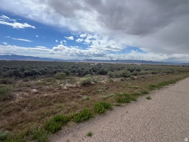 Expansive land parcel featuring natural shrubbery and distant mountain ranges under a broad sky