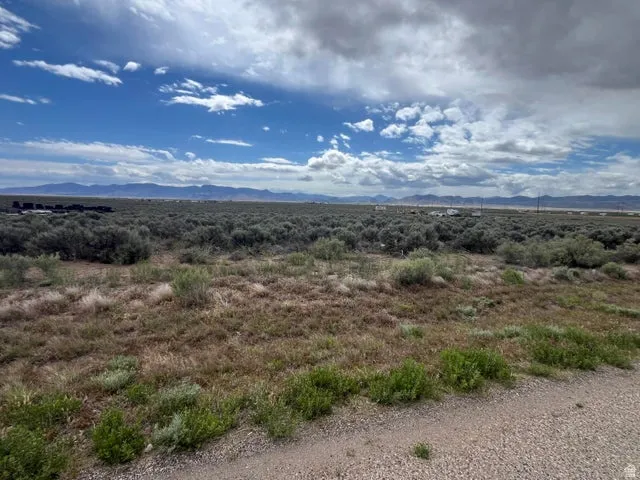 Expansive undeveloped land featuring natural desert vegetation, a gravel foreground, and distant mountains under a broad sky