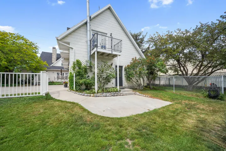 Exterior featuring white horizontal siding and a second-story balcony with black iron railing