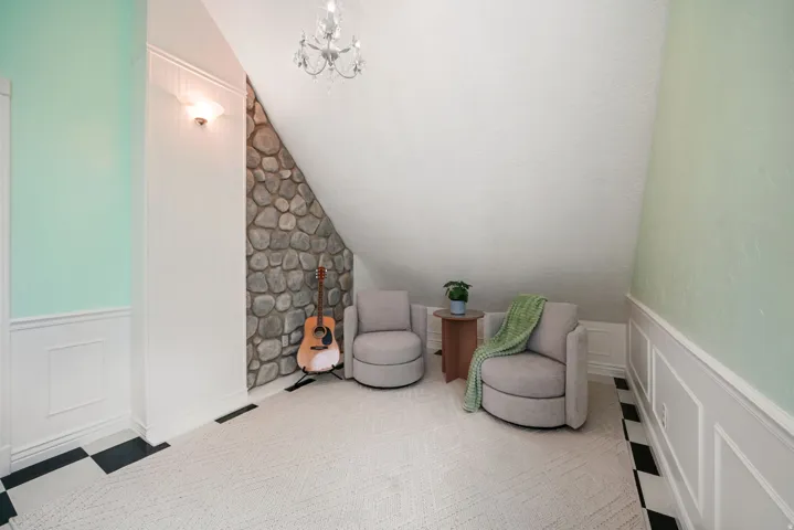 Room featuring a stone accent wall, sloped ceiling, and chandelier lighting