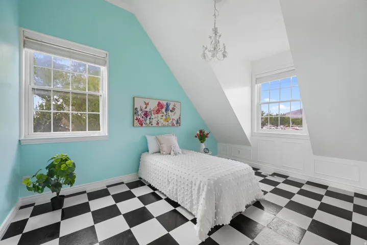 Room featuring a black and white checkered floor, angled ceilings, and two large windows