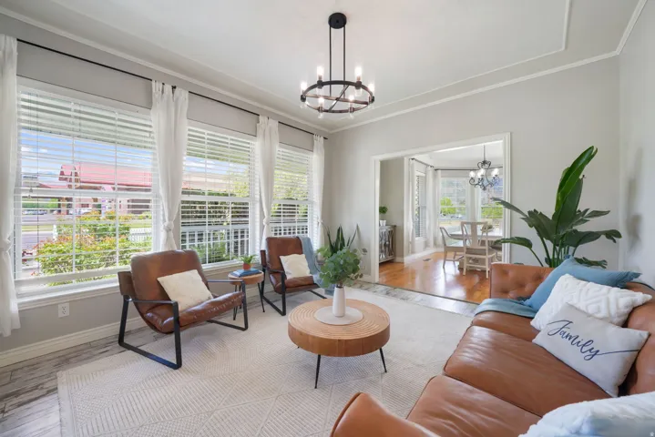 Spacious living area featuring multiple windows, a decorative ceiling with crown molding, and a modern chandelier