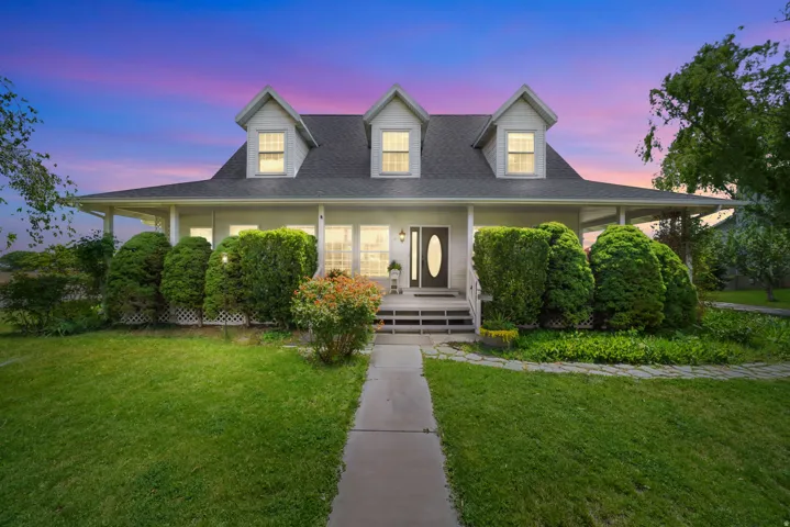 White exterior featuring a covered front porch and three dormer windows