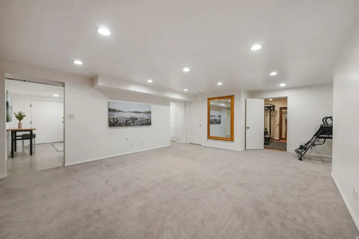 Spacious interior room featuring light-toned carpeting, recessed ceiling lighting, and crisp white walls