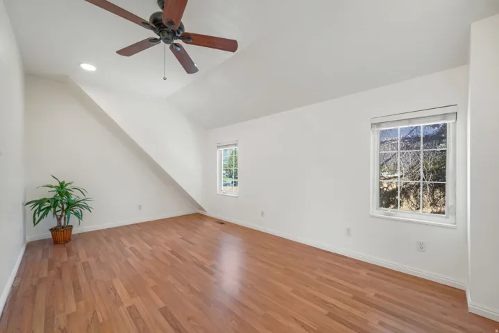 Spacious room featuring wood-finish flooring and a vaulted ceiling