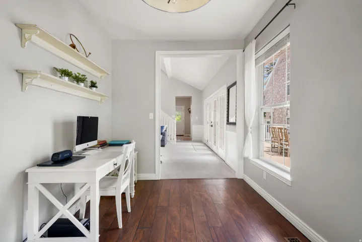 Spacious room with wood-finish flooring, light grey wall paint, and white trim