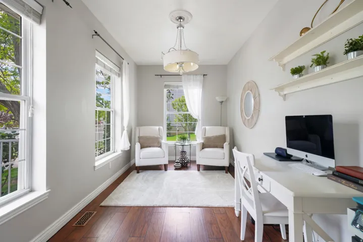 Spacious room featuring multiple double-hung windows, wood-finish flooring, light gray wall paint, a ceiling-mounted light fixture, and built-in wall shelves