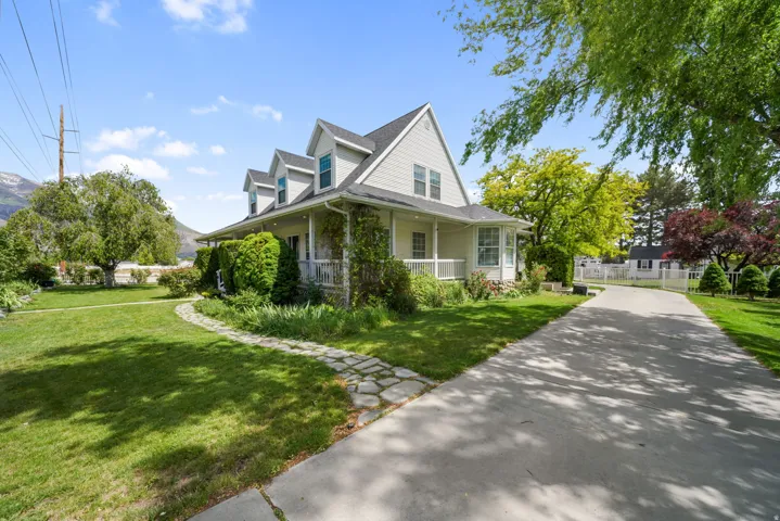 Two-story residence featuring dormer windows, a full-width covered porch, and a concrete driveway