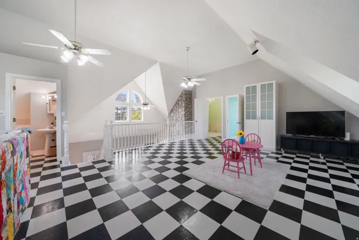 Spacious upper-level area featuring checkerboard flooring, a built-in storage cabinet, and a rounded arch window