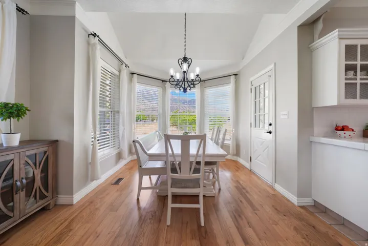 Dining area featuring wood-finish flooring, a bay window with mountain scenery, and a tray ceiling