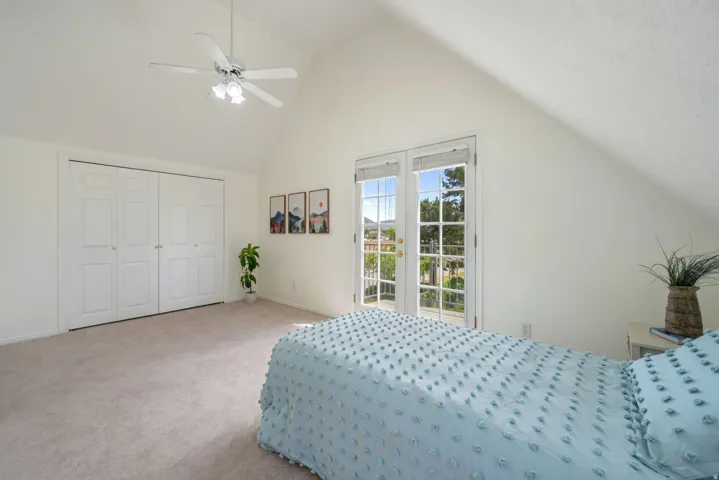 Bedroom featuring vaulted ceilings, light-colored carpeting, and a ceiling fan with integrated lighting