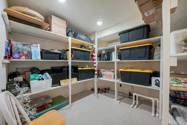 Expansive storage area featuring built-in shelving, white walls, recessed lighting, and light-colored flooring