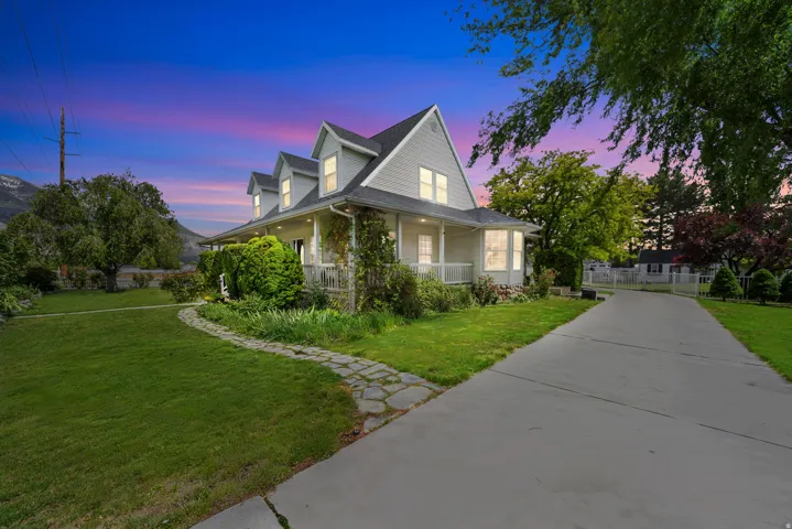 Two-story residence featuring a covered front porch, dormer windows, and a light-colored exterior