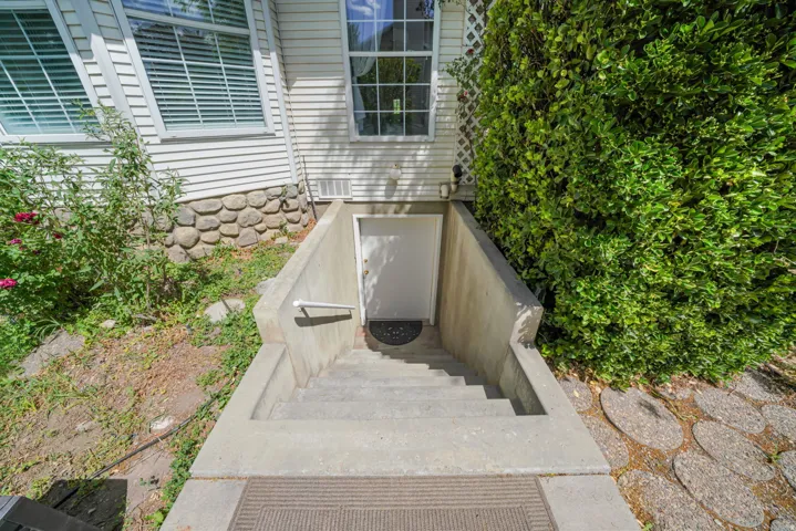 Concrete exterior staircase leading to an entry door, featuring a white handrail