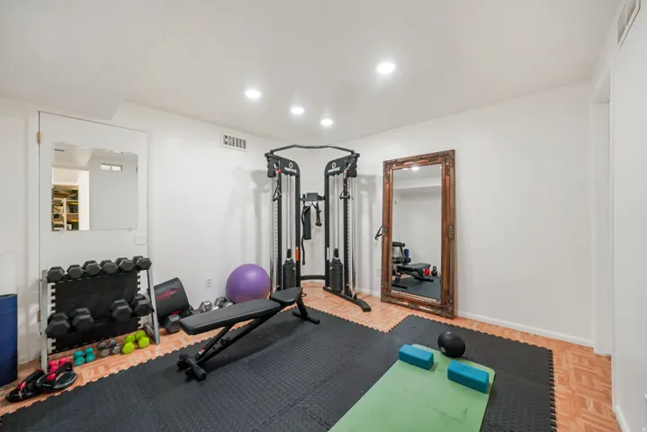 Spacious room with recessed lighting and neutral walls, featuring light wood-finish flooring and black interlocking floor mats