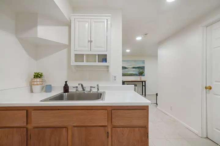 Utility sink with a stainless steel basin, white countertop, and wood-finish lower cabinetry