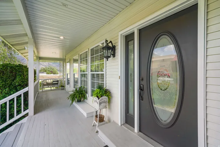 Covered front porch featuring a dark entry door with an oval decorative glass insert and a sidelight
