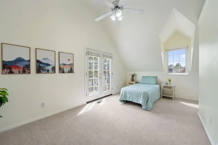 Room featuring vaulted ceilings with a ceiling fan, plush carpeting, and a window dormer