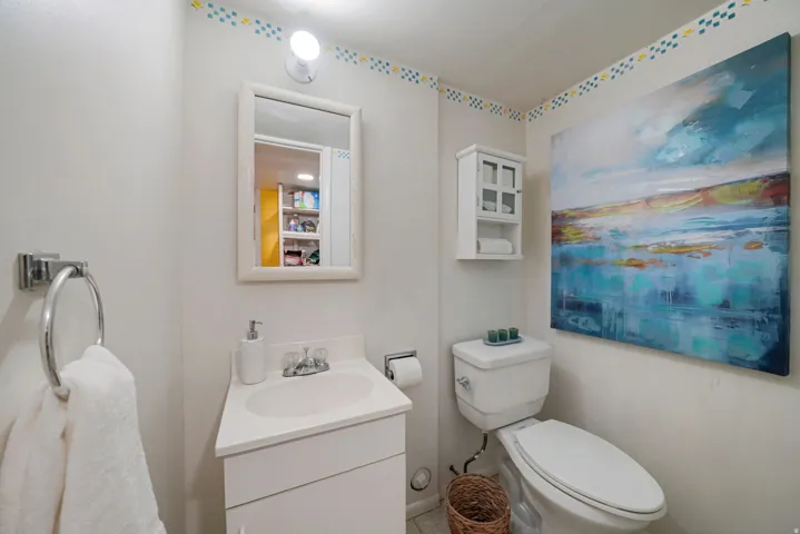 Compact bathroom featuring a white vanity with integrated sink, chrome faucet, and framed mirror