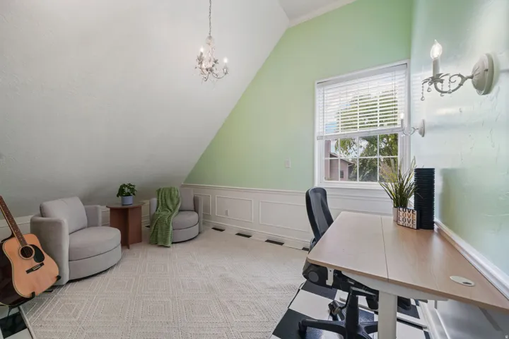 Room featuring vaulted ceilings, a window with blinds, decorative wall sconces, a chandelier, and wainscoting